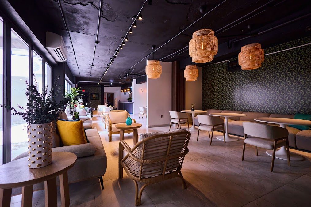 Wide view of the lounge at Ola Boutique Hotel with tables, sofas and woven pendant lamps
